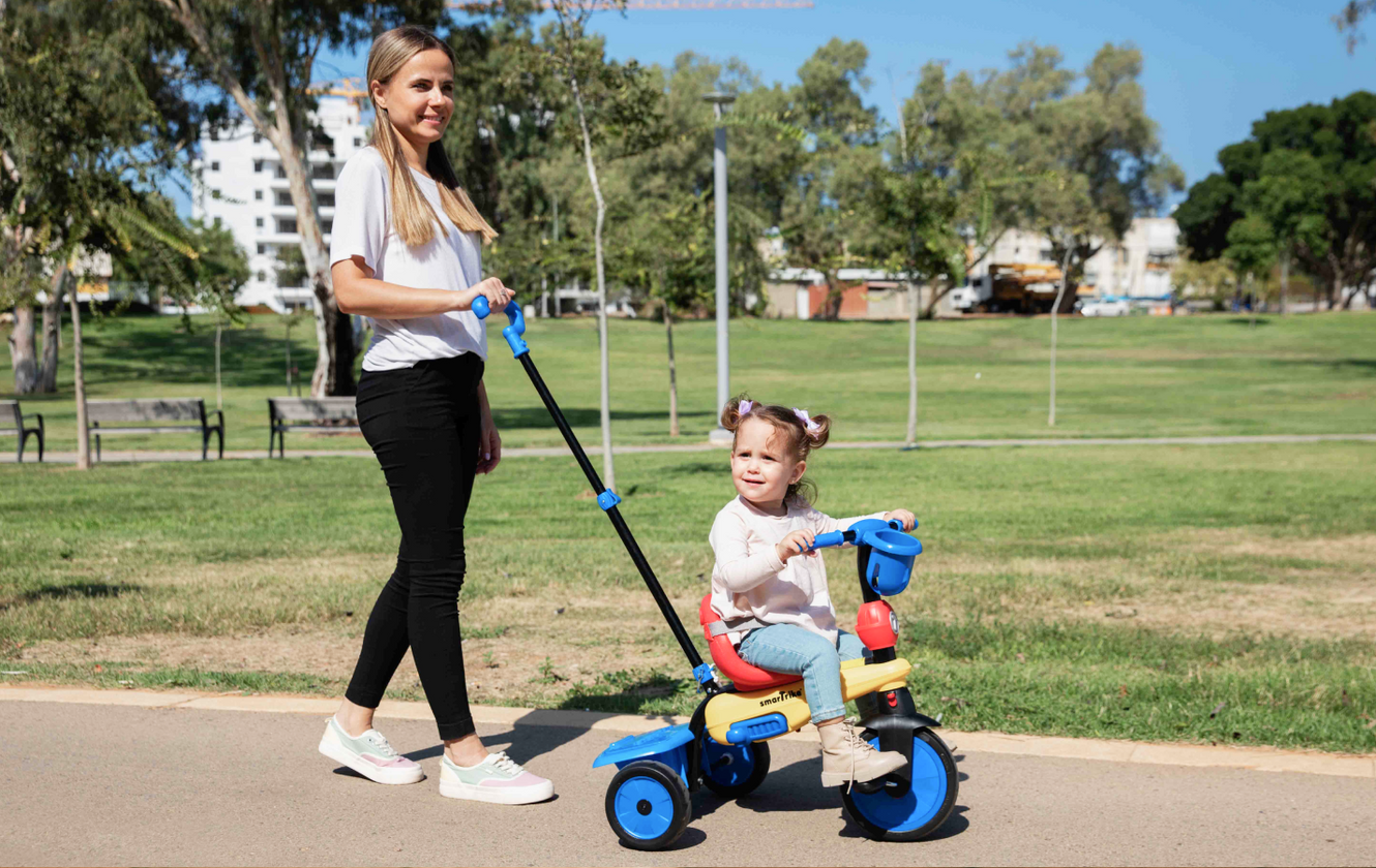 a woman pushing a child on a tricycle