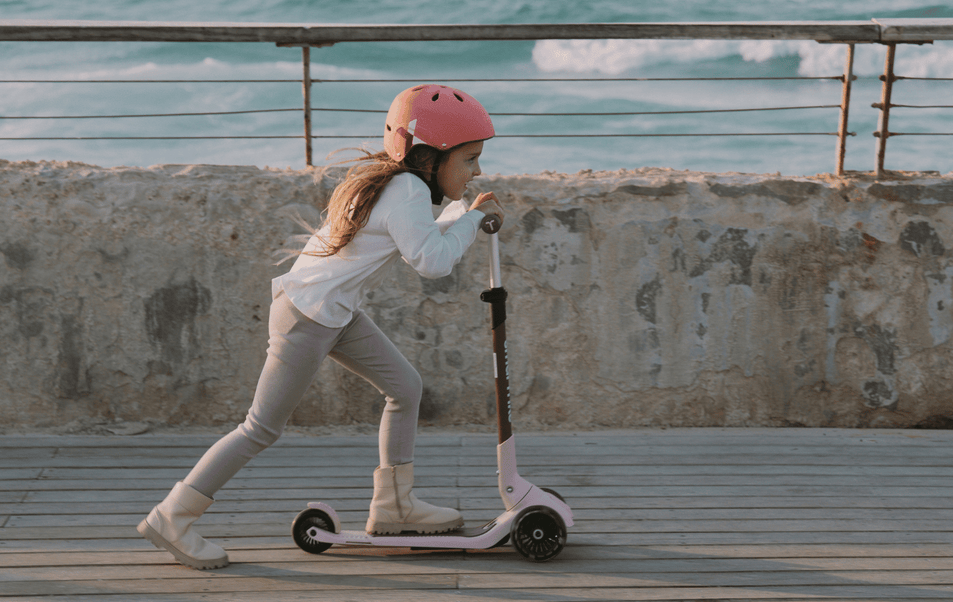 a girl wearing a helmet and riding a scooter